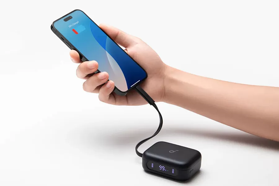A smartphone is charged via a short USB-C cable from the Anker Soundcore P41i earbud charging case held in a hand.
