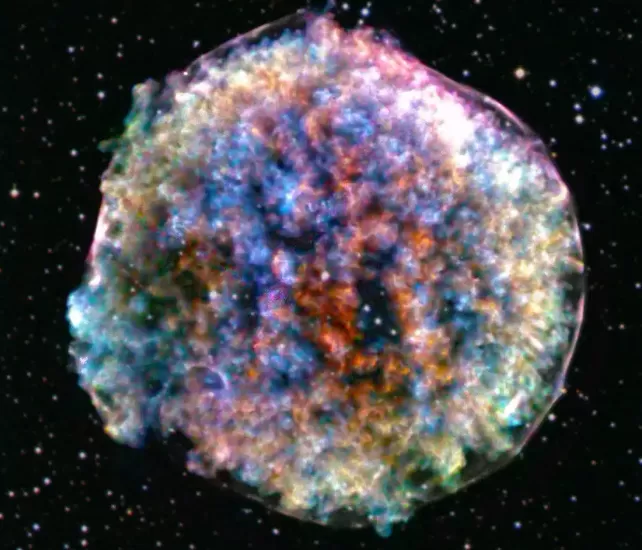 Colorful image of the Tycho supernova remnant showing gas expanding from a stellar explosion, relevant to cosmic ray research