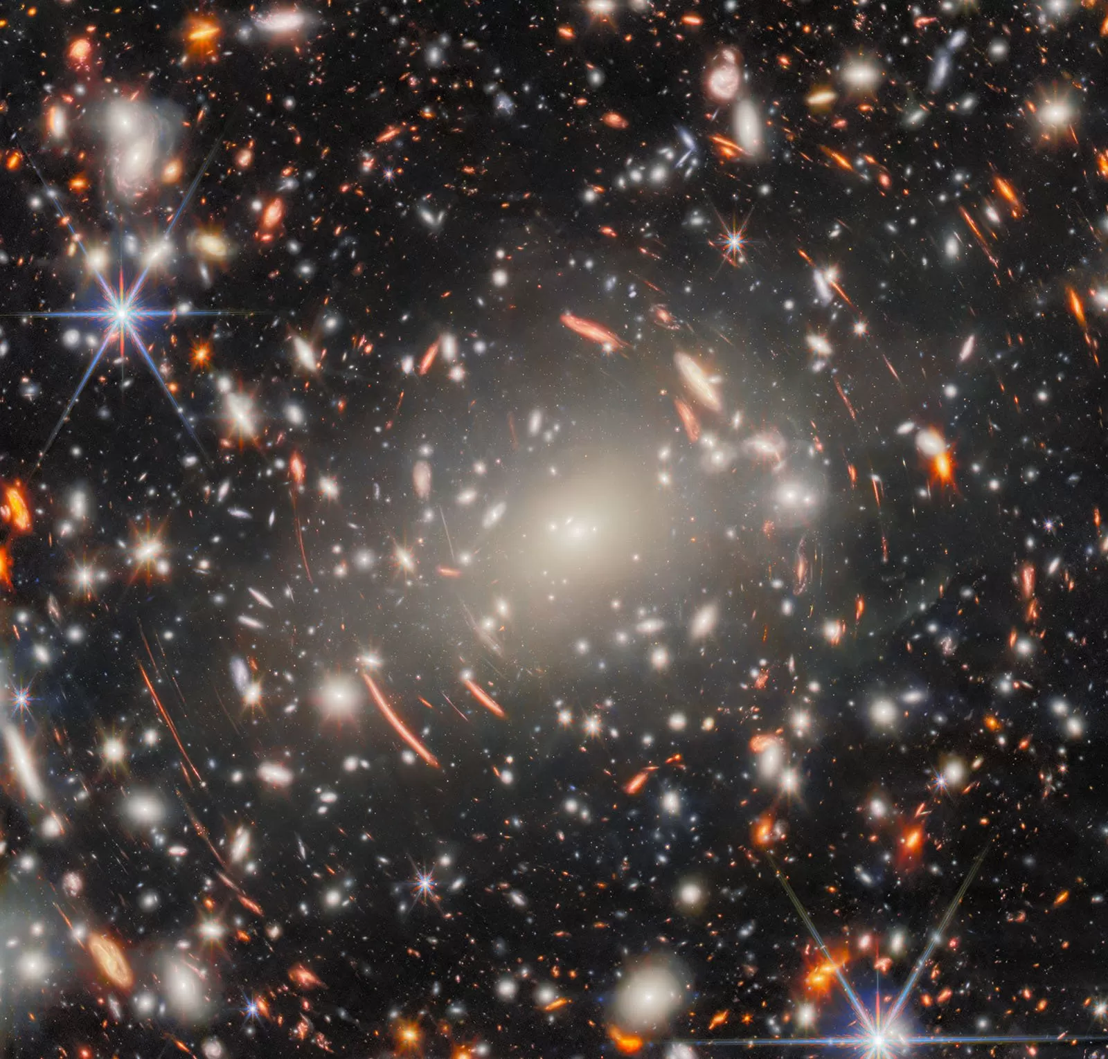James Webb Space Telescope image shows light warped around galaxy cluster Abell S1063, revealing distant galaxies as bright arcs in deep space.
