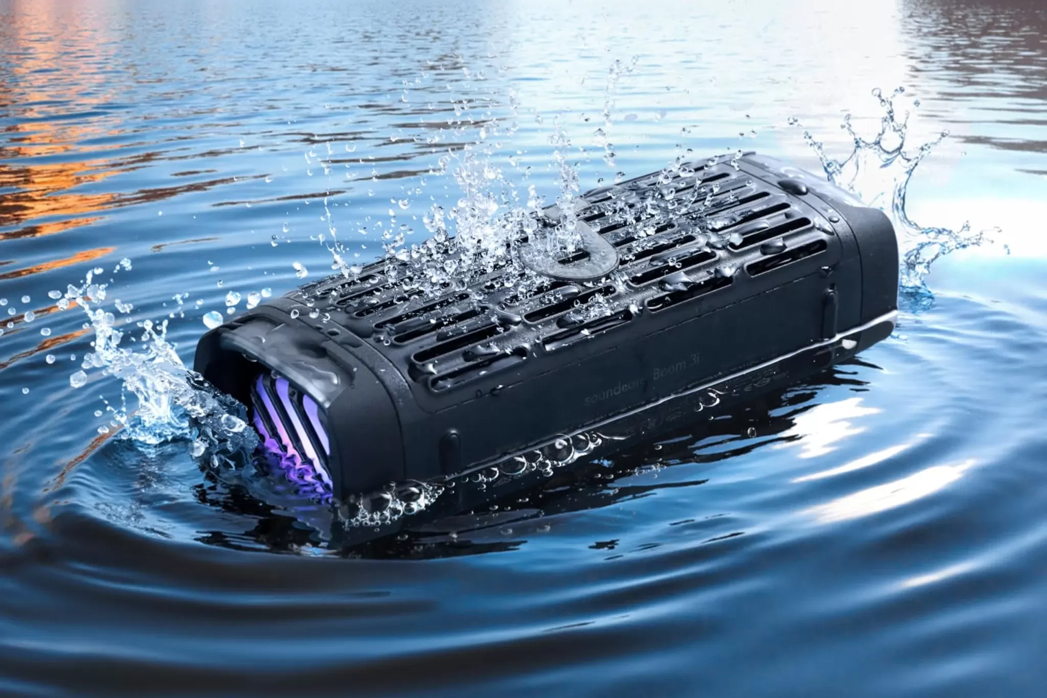 Anker's Boom 3i wireless speaker floating in a lake with trees and hills in the background.