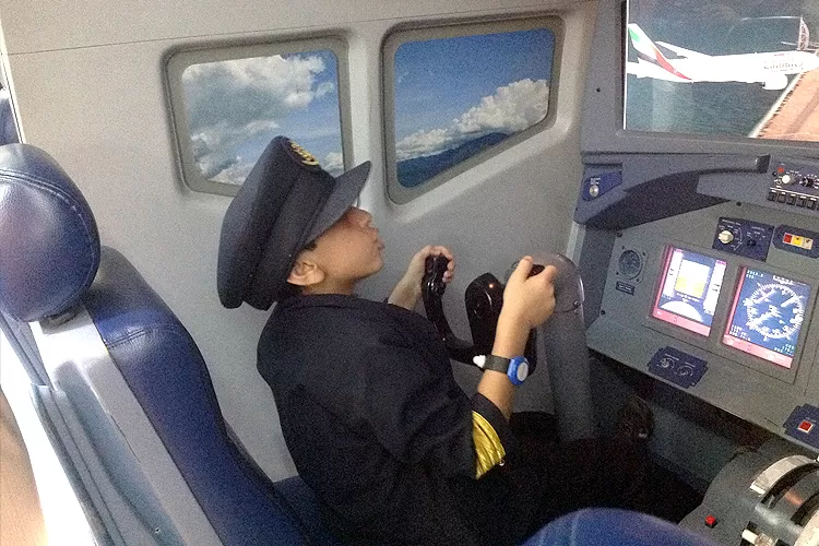 Young Hasaan Mohsin sitting in a Boeing 777 flight simulator, showing early interest in aviation.