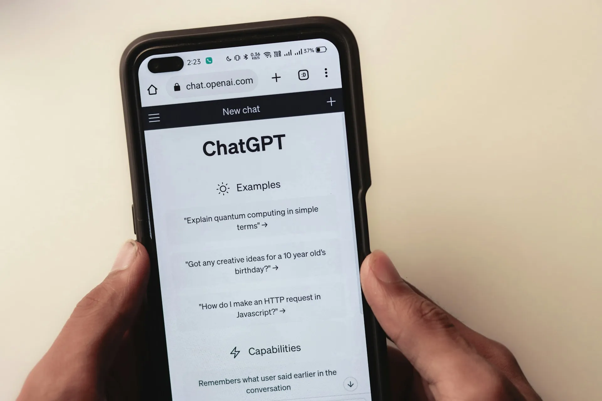 Hand holding mobile phone displaying a conversation with the ChatGPT AI chatbot